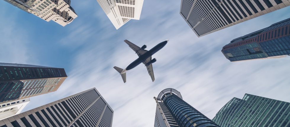 stock photo jet plane aircraft traveling in the sky over city buildings in downtown travel destination of 613955513